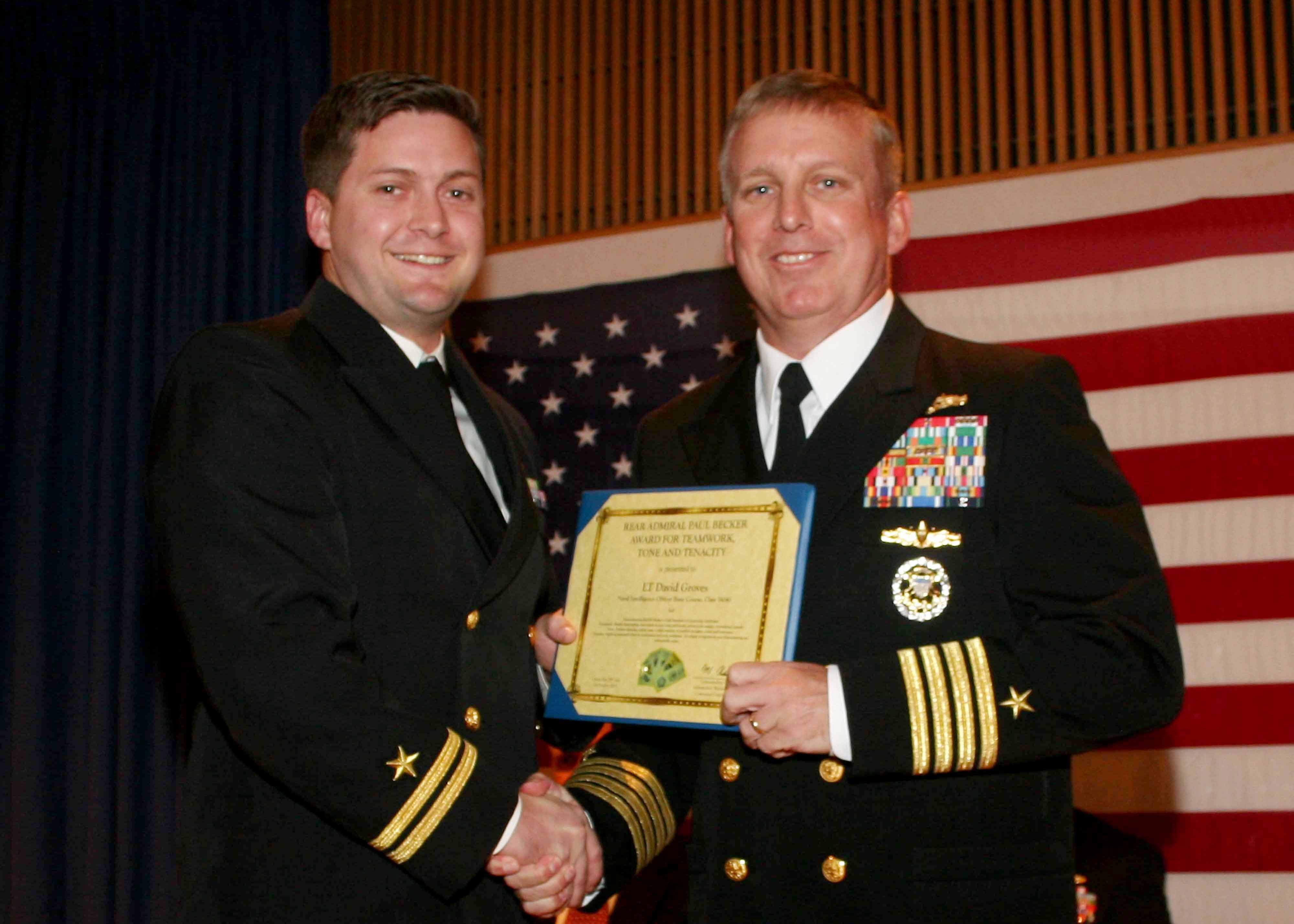 Lt. David Groves receives the Rear Adm. Paul Becker "Teamwork, Tone, Tenacity" award from Capt. Mark Kester during the Naval Intelligence Officer Basic Course (NIOBC) graduation at  Information Warfare Training Command (IWTC) Virginia Beach, Oct. 28, 2016.  The new award is named after Becker's decade's long emphasis on his pillars of leadership.  NIOBC has been taught at Layton Hall at the Dam Neck Annex since 1986 and graduates 121 students on average every year. Photo courtesy of U.S. Navy.