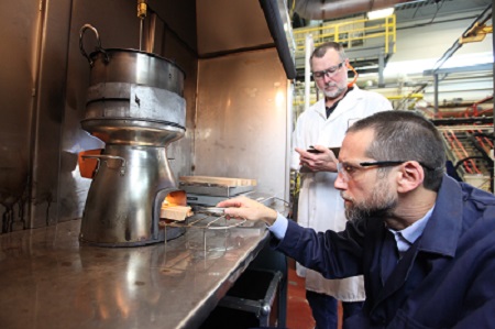 Two researchers examine a clean-burning cookstove design in a lab.