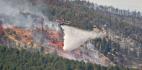 Helicopter spreading water over a forest fire.