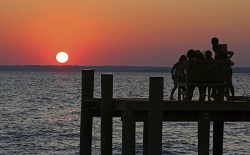 Silhouette of kids on dock at sunset