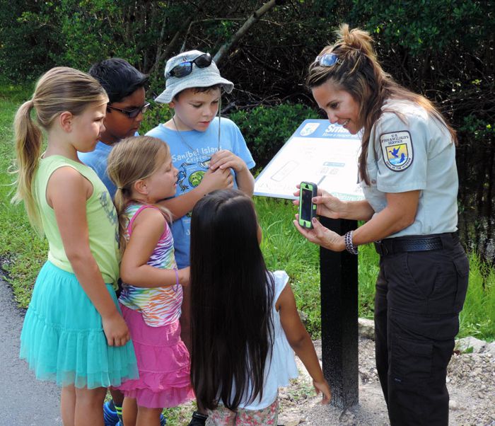 A USFWS employee shows a group of children the iNature app at a National Wildlife Refuge