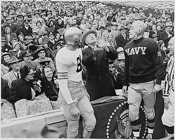 President Harry S. Truman tosses a coin in the air before the annual Army-Navy football game in Philadelphia, Dec. 2, 1950, as the captains of the Army and Navy teams watch.  Photo Credit: National Archives 