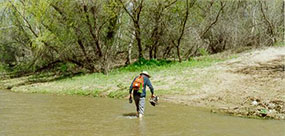 man wading across river