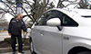 Photo of a man plugging an electric vehicle into a charging station.