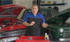 Photo of a man talking in front of classic cars.