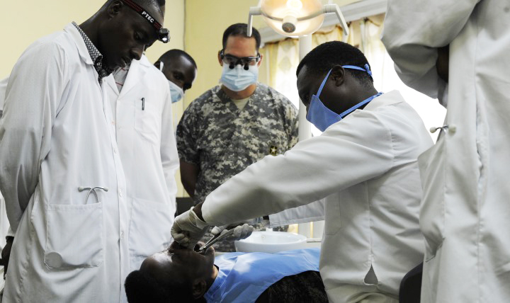 U.S. Army Capt. Cody Negrete, a general dentist assigned to the Functional Specialty Team Bravo 407th Civil Affairs Company, along with Hope Africa University students, observe Burundi National Defense Force Col. Bizimana Athanase, oral surgeon, perform a routine filling on a man at Kamenge Military Hospital in Bujumbura, Burundi. Negrete traveled to Burundi to participate in a military health engagement meant to share best practices with the BNDF and their medical providers. (U.S. Air Force photo by Staff Sgt. Jocelyn A. Ford)