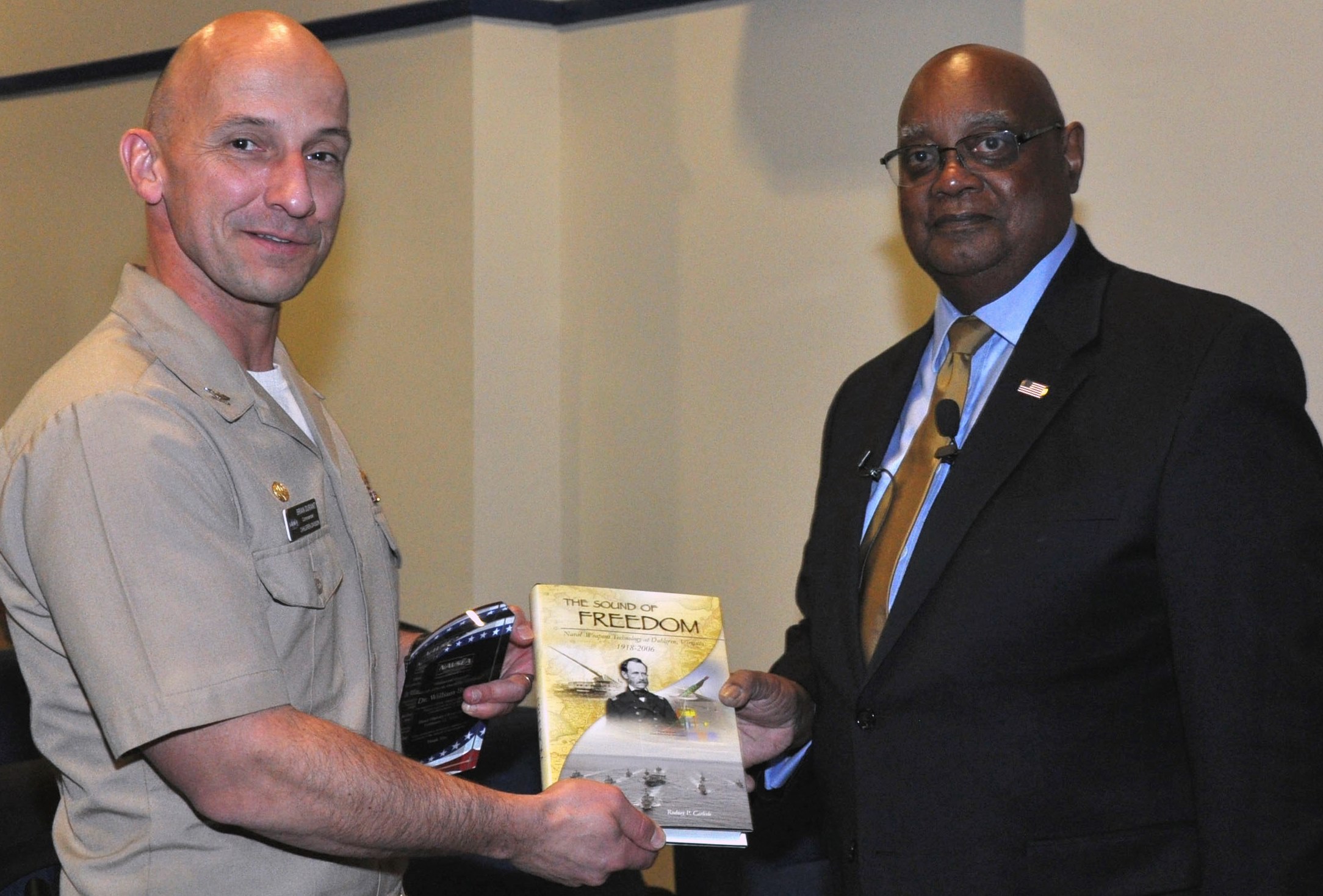 DAHLGREN, Va. - Capt. Brian Durant, Naval Surface Warfare Center Dahlgren Division (NSWCDD) commander, presents the Dahlgren history book, "The Sound of Freedom," to Dr. William Bundy, Gravely Naval Warfare Research Group director, at the 2016 Black History Month Observance, Feb. 11.  "The research and development progress that was shared with me on the railgun and directed energy systems was very reassuring," said Bundy, a U.S. Naval War College professor who toured NSWCDD electromagnetic railgun and directed energy facilities after inspiring a military and civilian audience with his keynote speech at the observance. "Those capabilities will certainly deliver advantages for our maritime forces.  It was absolutely encouraging to witness first-hand the remarkable effort and work that is continuing today at Dahlgren." U.S. Navy photo by Barbara Wagner.