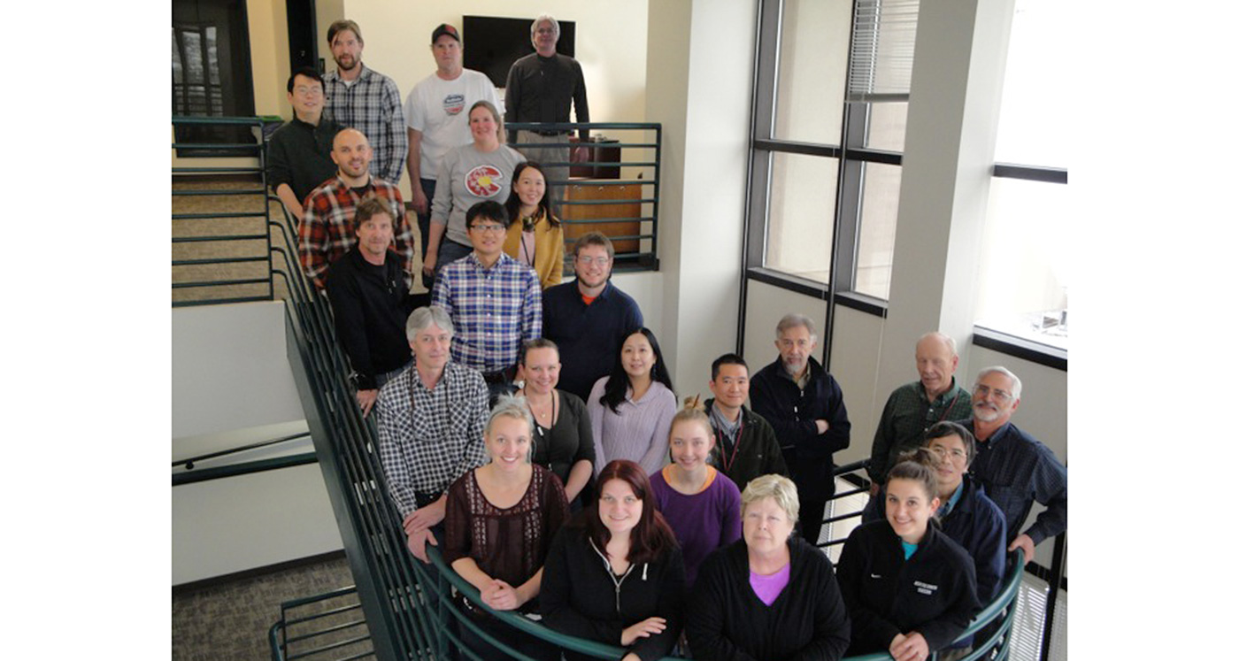 Photo of a group of men and women standing along a spiral staircase in an office setting.