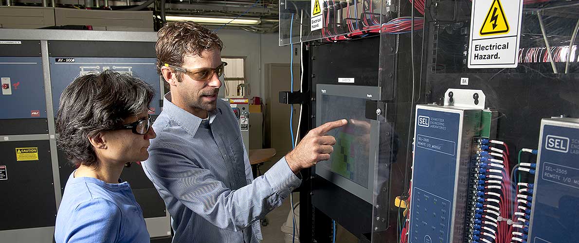 A photo of a man and woman looking at a monitor that shows microgrid integration.