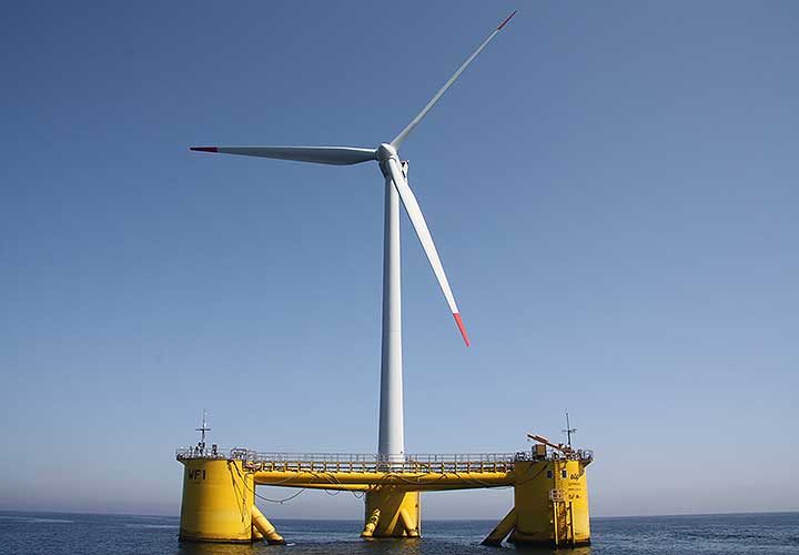 A photo of a singular wind turbine on a yellow floating turbine base in calm water.