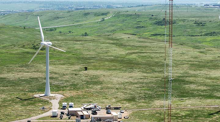 An aerial photo of two wind turbines and a meteorological tower against green landscape at the National Wind Technology Center.