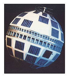 Photo of a white satellite with 11 blue squares on top, and 14 blue squares on the bottom. Two horizontal metal bars separate the top from the bottom of the satellite.