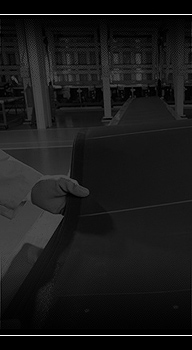 Photo of a hand with a blue glove holding a long, rectangular, black and blue film panel.