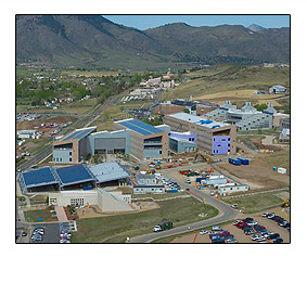 An aerial photo of several buildings clustered together in front of a mountain range.