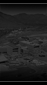 An aerial photo of several buildings clustered together in front of a mountain range.