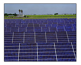 Photo of several rows of horizontal, blue and white, rectangular panels  with a green and blue landscape displayed behind the panels.