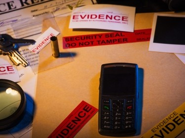 Police desk with crime case records containing a mobile phone, photos, and keys