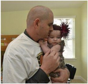 Retired Sgt. Ron Wiley holds his infant daughter in the Family’s new mortgage-free home, donated by a local non-profit.