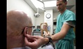 Air Force Maj. Stephen Cherrington (right), 59th Dental Group maxillofacial prosthodontist, checks the fitting of retired Army Master Sgt. Todd Nelson’s prosthetic ear at the San Antonio Military Medical Center, Joint Base San Antonio-Fort Sam Houston, Texas. 