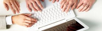 Several sets of hands on a laptop keyboard.