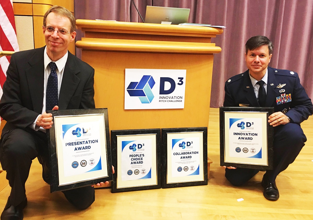 Paul Jaffe (left), spacecraft engineer at the U.S. Naval Research Laboratory, and team member Col. Peter Garretson, U.S. Air Force, display placards for award categories won during the first Department of Defense  ‘Diplomacy, Development, and Defense (D3) Innovation Challenge. The team comprised of federal, military, and private entities, led by Dr. Jaffe, received four of the seven possible awards for the categories of Innovation, Presentation, Collaboration, and People’s Choice for their innovative concept of space-based solar energy harnessed to power terrestrial assets. Photo by U.S. Naval Research Laboratory 