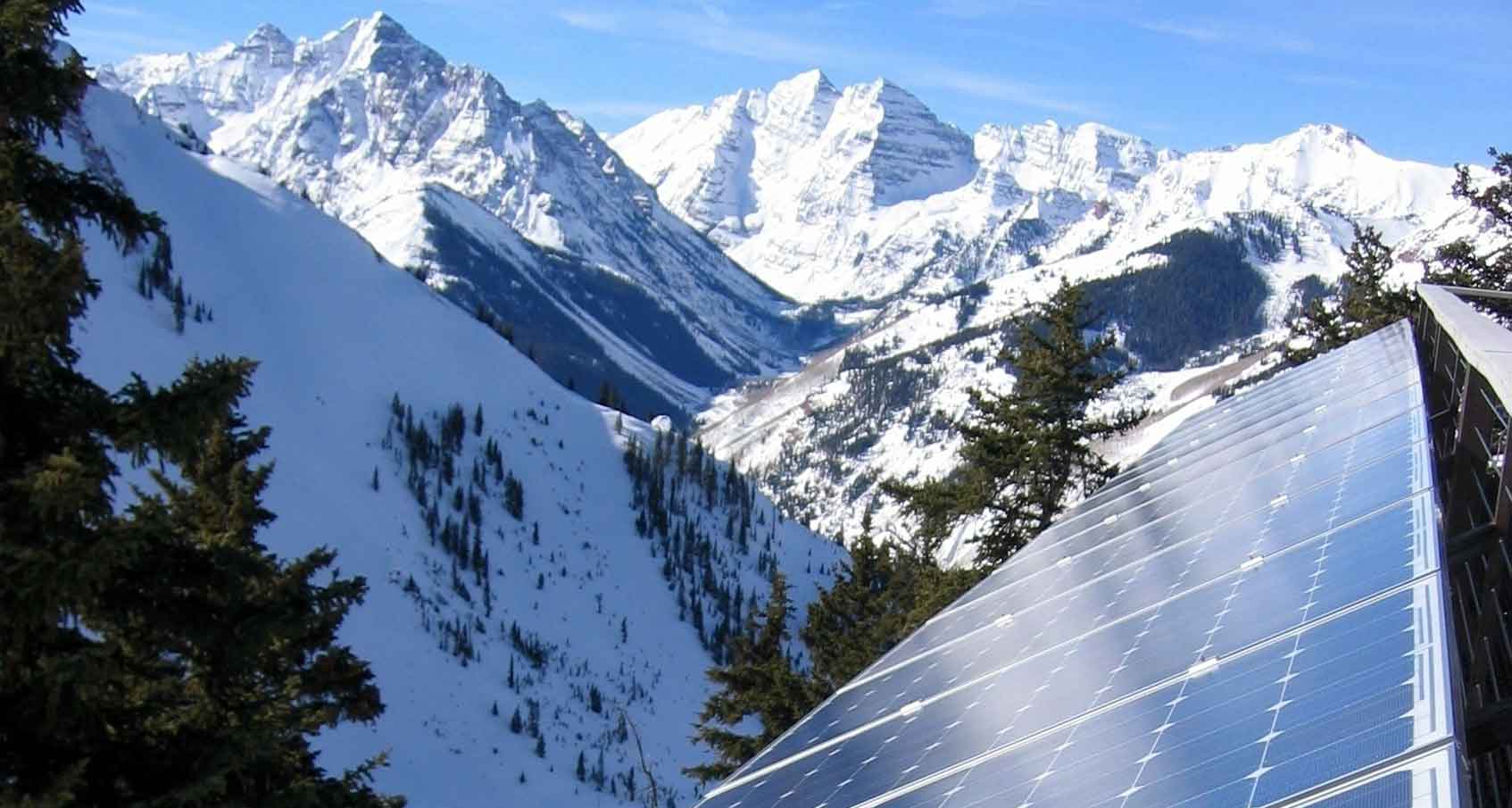 Photo of a solar electric system in Colorado with snow-covered mountain peaks in the background.