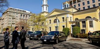 Men and cars in front of yellow church (© AP Images)