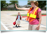 A crossing guard helps small child across street. 