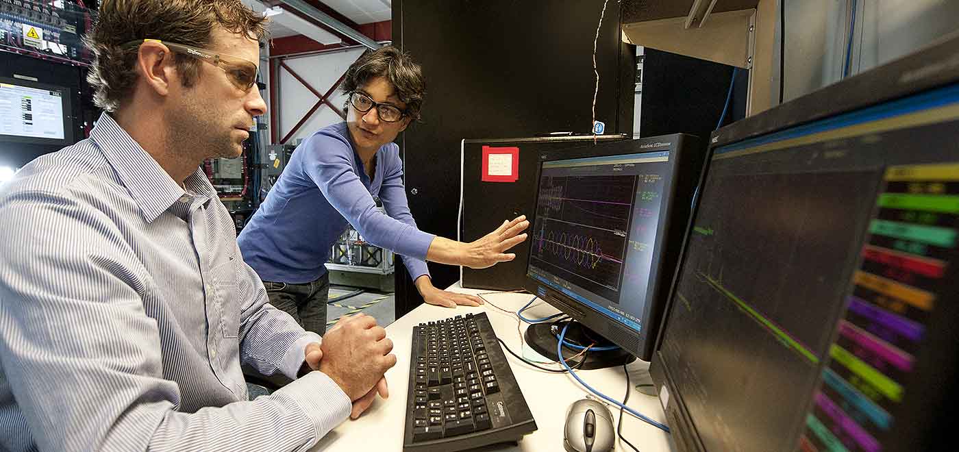 Photo of two people talking and looking at computer screens.