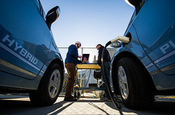 Photo of two hybrid cars at a fueling station.