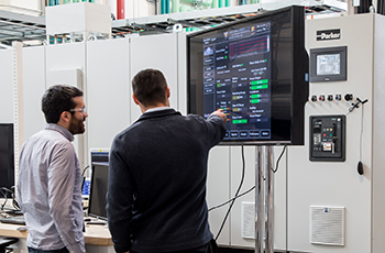 Photo of two men discussing data on a monitor.