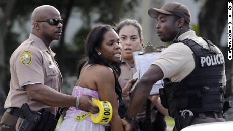 A concerned mother is meet by Miami-Dade police officers as she searches for her child after several were injured in a shooting at Martin Luther King Jr. Memorial Park in Miami-Dade, Fla., Monday, Jan. 16, 2017. The Miami Herald reports that hundreds of people had gathered in the park after the annual MLK Day parade. (Carl Juste/Miami Herald via AP)