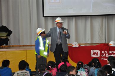Ralph Tinari, Deputy Chief, Construction, U.S. Army Corps of Engineers, New York District has a student volunteer wear some of the safety gear engineers are required to wear on the job. 