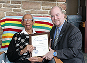 A hospital worker presents a senior man a plaque