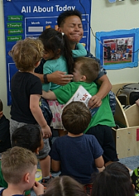 Preschool students give Rear Adm. Bette Bolivar, the Commander of Joint Region Marianas, hug following a book reading.