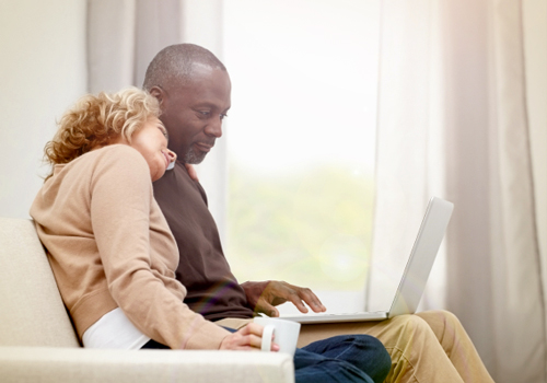  a couple sitting together on a sofa looking at their mySocialSecurity account