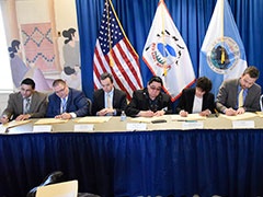 A group of people seated at a table signing documents.