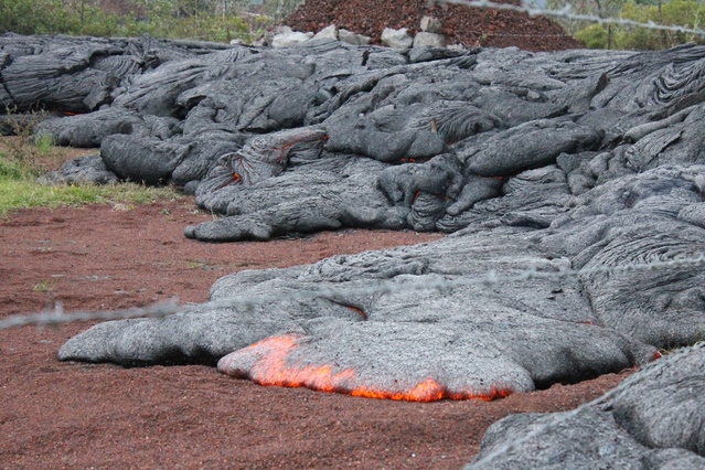 Close up of red hot lava flowing on a dirt road.