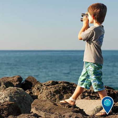 photo of a boy with binoculars looking out into the ocean