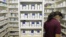 FILE - A pharmacy employee looks for medication as she works to fill a prescription.