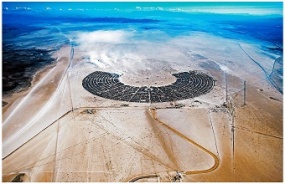 Aerial photograph of Black Rock City in 2015, an enormous crescent-shaped campground on the pale desert floor.