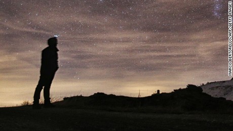 A photographer looks at the sky at night to see the annual Geminid meteor shower on the Elva Hill, in Maira Valley, near Cuneo, northern Italy on December 12, 2015.  AFP PHOTO / MARCO BERTORELLOMARCO BERTORELLO/AFP/Getty Images