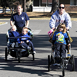 Two mothers pushing jogging strollers with children