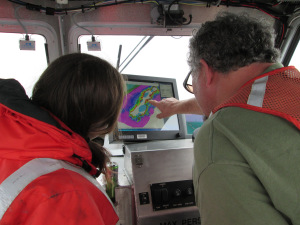 Hydrographer in Charge (HIC) Starla Robinson and Seaman Surveyor Dennis Brooks look over multibeam data together, as they safely plan next steps to survey in shoal, rocky waters. 