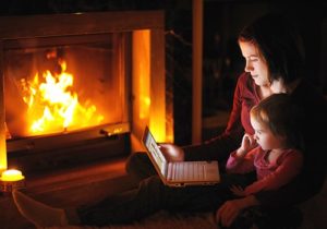mother and daughter on computer by fireplace