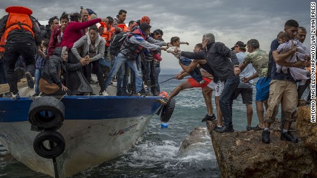 Refugees and migrants get off a fishing boat at the Greek island of Lesbos after crossing the Aegean Sea from Turkey on Sunday, October 11.