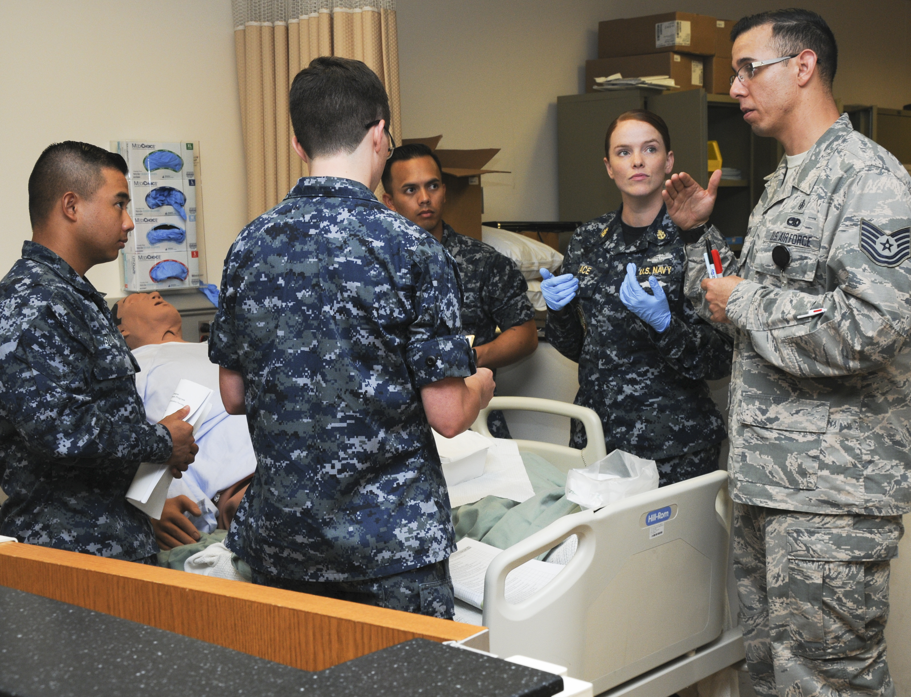 SAN ANTONIO (Sept. 20, 2016) Air Force Tech. Sgt. Rey Meza, an instructor at the Medical Education and Training Campus (METC), talks to students alongside his fellow instructor, Chief Hospital Corpsman Jacklyn Place, during a nursing lab portion of the Basic Medical Technician Corpsman Program (BMTCP) at METC on Joint Base San Antonio - Fort Sam Houston. The joint program prepares Navy hospital corpsman and Air Force medical technicians with the basic medical knowledge to perform in an emergency or nursing scenario. (U.S. Navy photo by Mass Communication Specialist 1st Class Jacquelyn D. Childs)