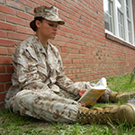 Female service member reading a text book.