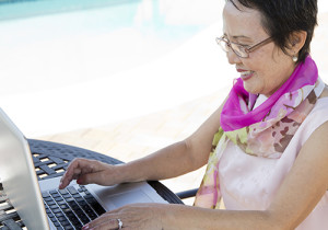 A woman sits at her computer on the beach