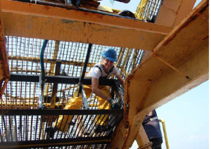 I am wearing my bib and overalls, boots, and a hardhat while working inside the dredge to free the clams caught in the corners and cracks of the dredge. 